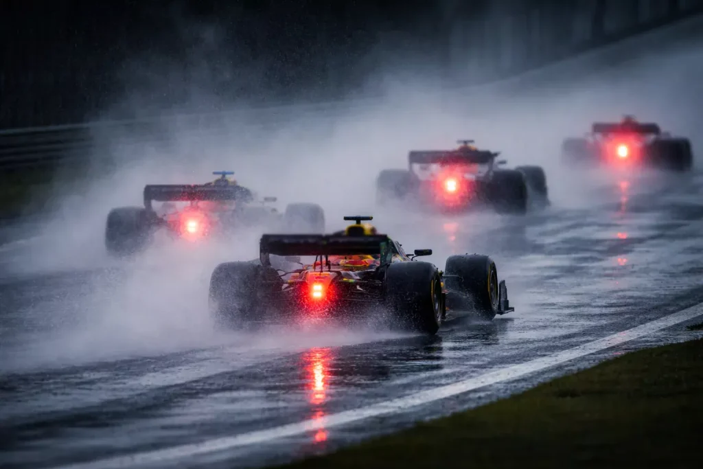 Monoplazas de F1 corriendo bajo una intensa lluvia con spray de agua