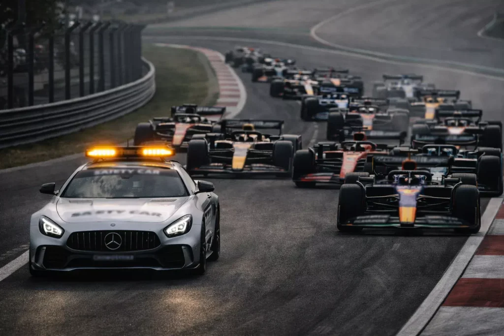 Safety car de F1 liderando el pelotón con luces naranjas encendidas en pista